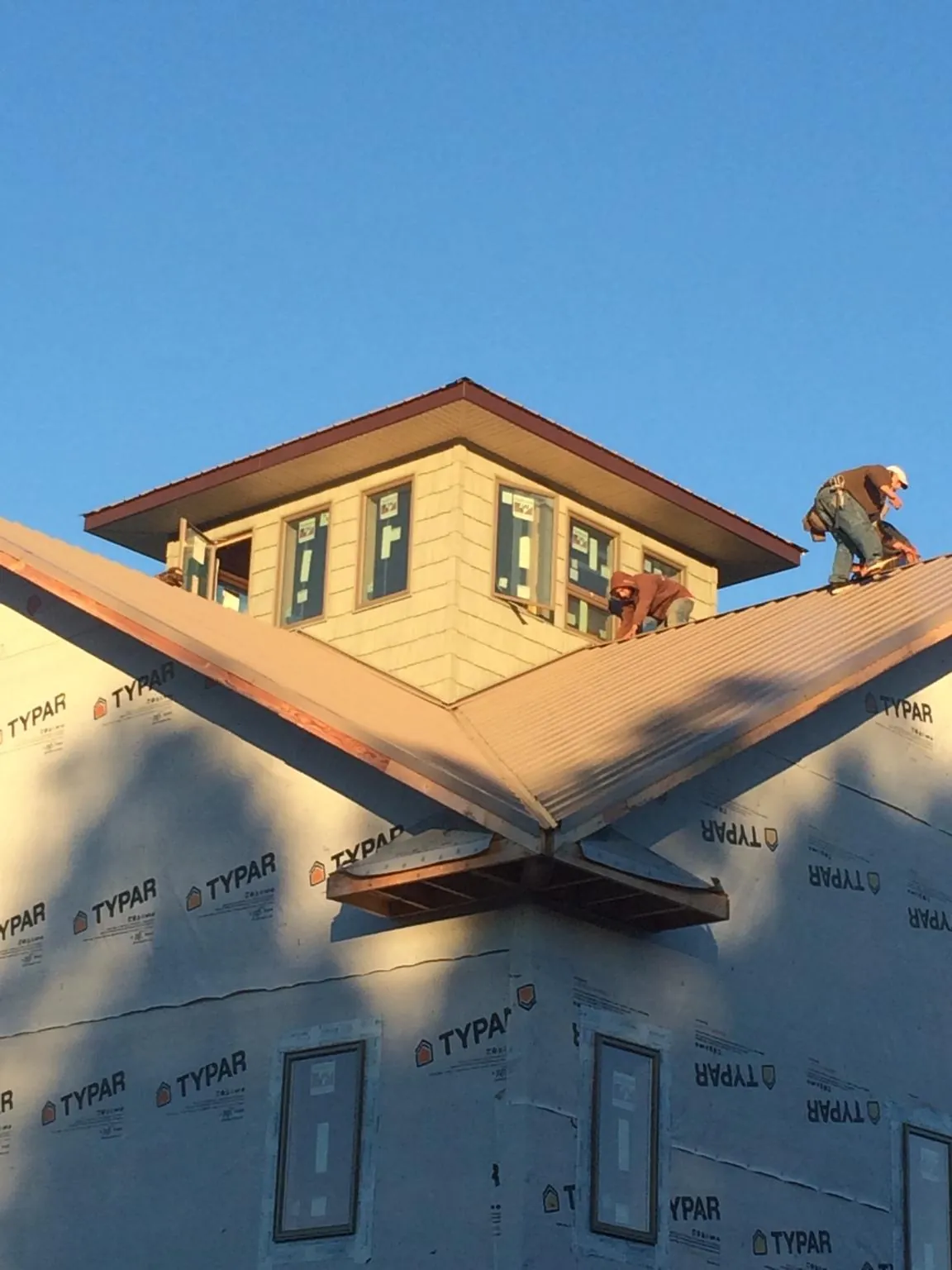 Roofers working around a rooftop cupola on a new metal roof at sunset — Roof Waterproofing in Oxford by Roofing Brothers
